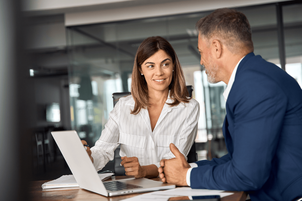 Latin business man and European business woman discussing project on laptop in office