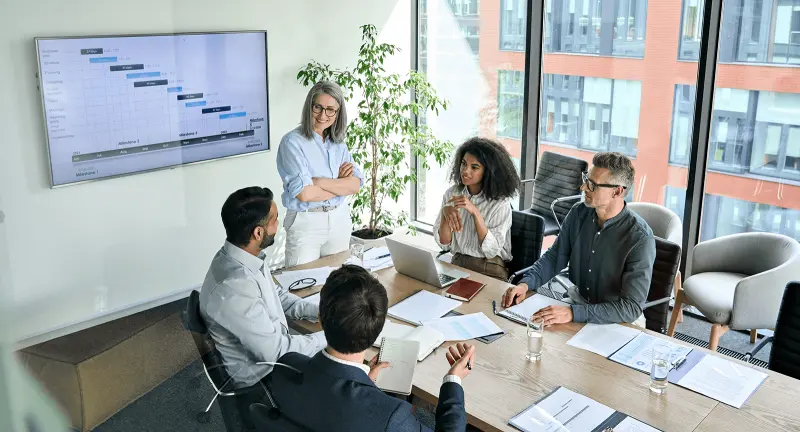 Senior female and multicultural business people discussing company presentation at boardroom table