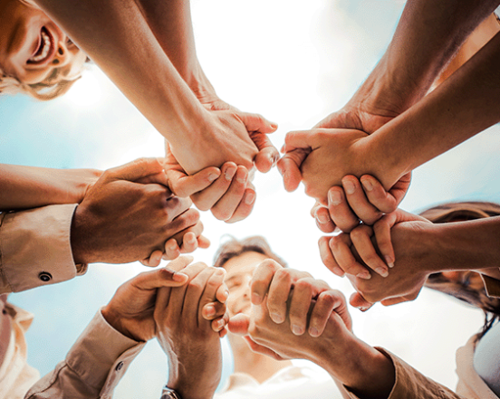 Multi ethnic group of young people holding hands outdoors